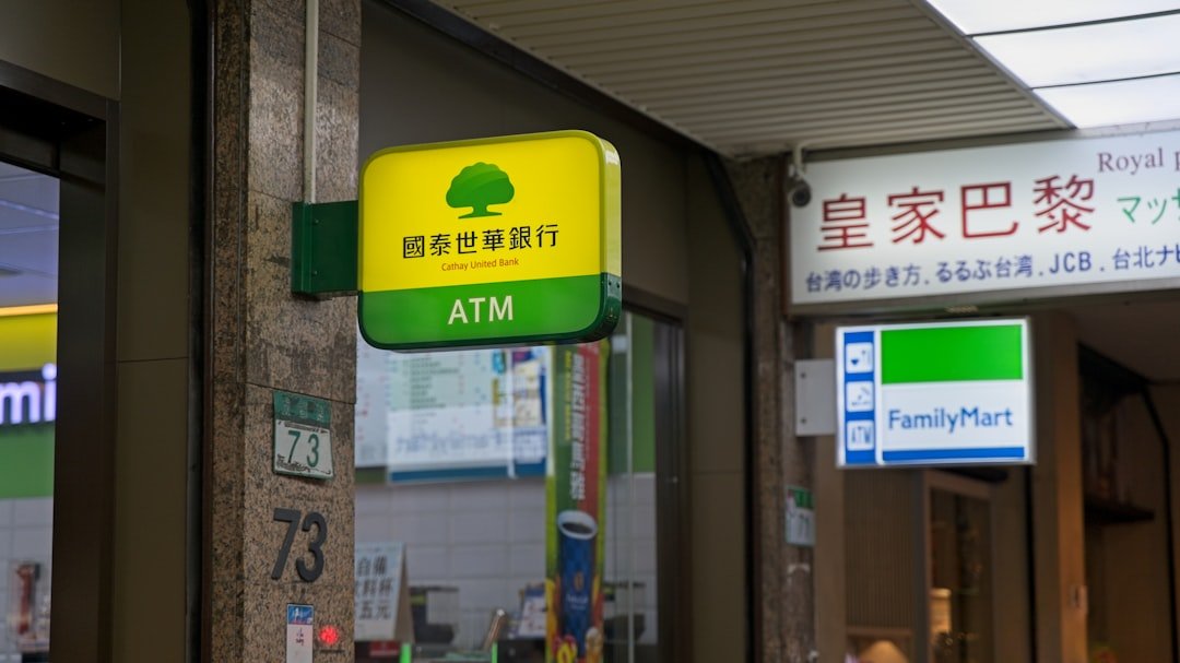 a green and yellow atm sign on a building