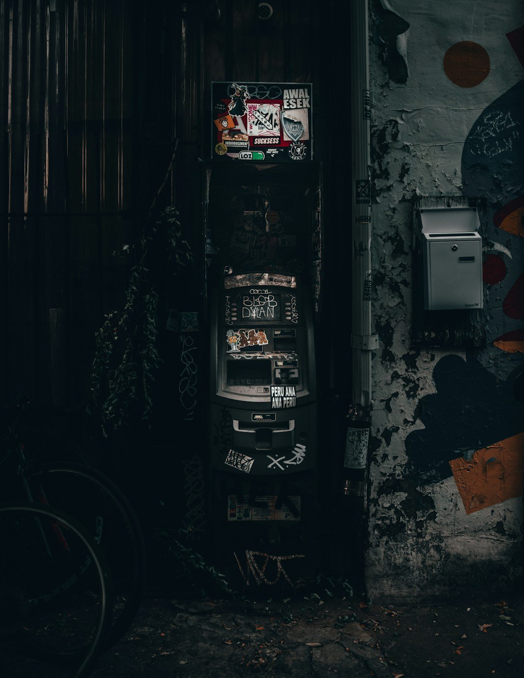 a vending machine sitting next to a wall with graffiti on it
