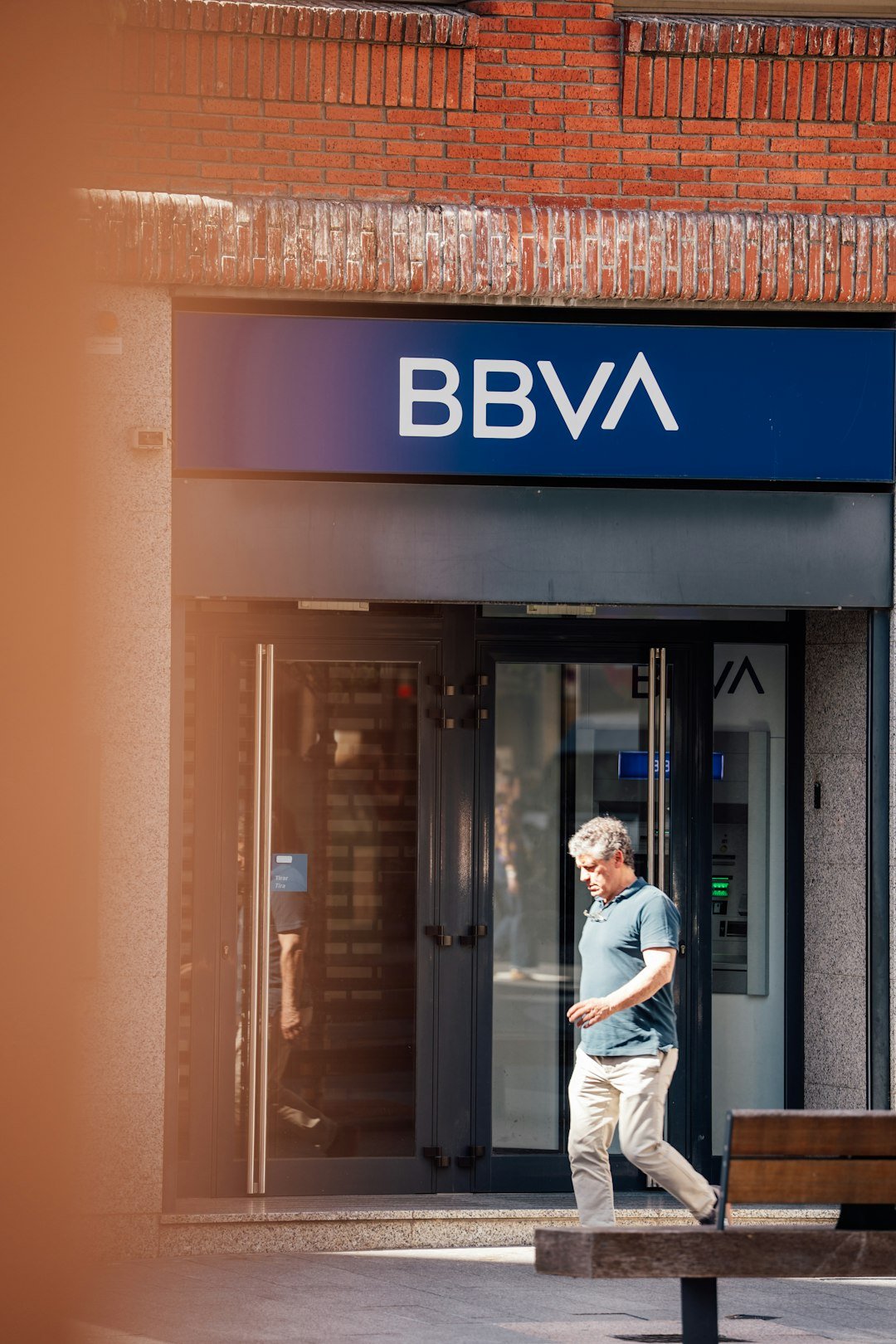 Man walks past a bbva bank entrance.