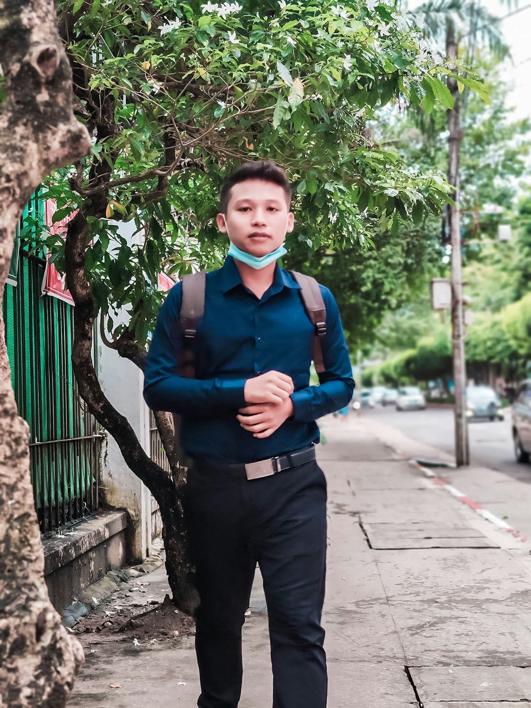 man in blue long sleeve shirt and black pants standing near green tree during daytime
