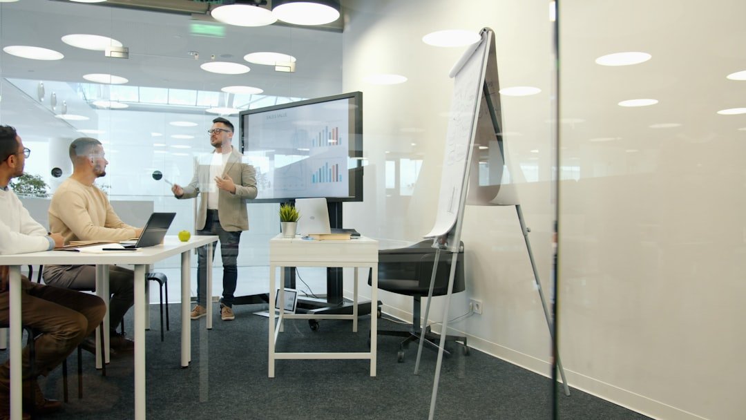 Man presenting to colleagues in a modern office meeting.