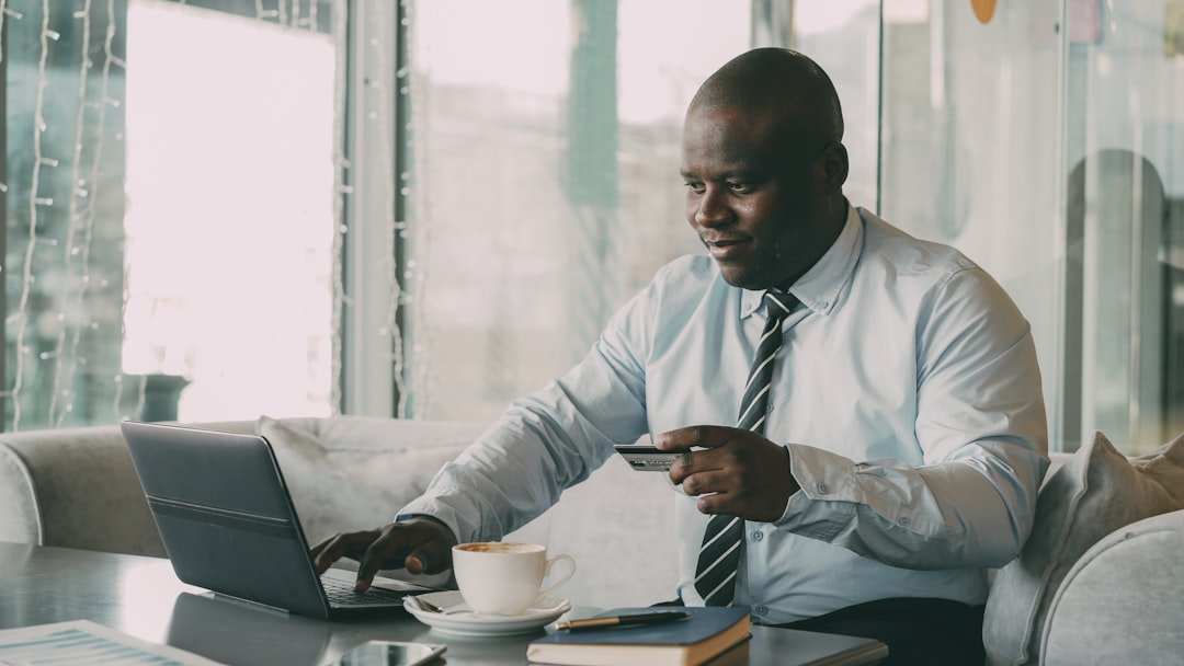 Man in shirt and tie using laptop and credit card.