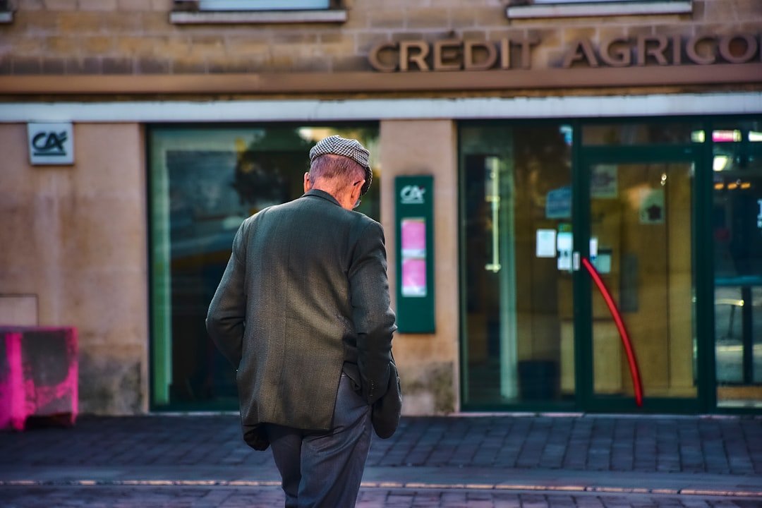 Man walks towards a crédit agricole bank entrance.