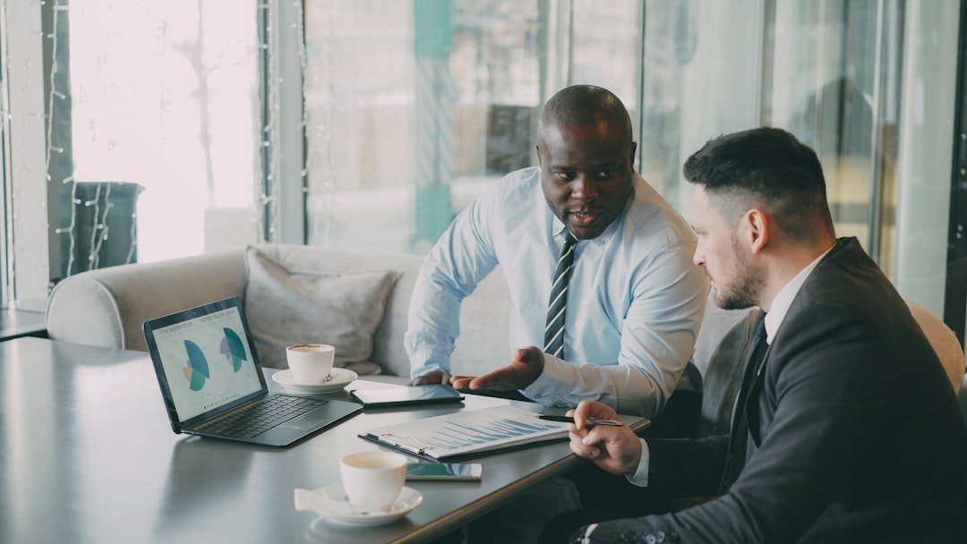 Two businessmen discussing charts on a laptop.