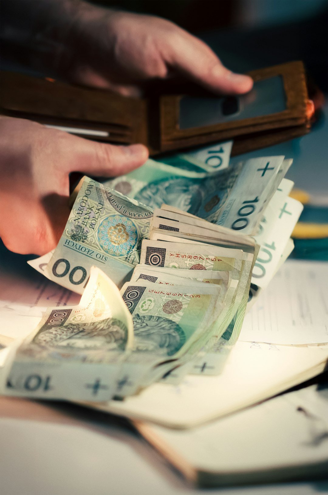Hands holding polish zloty banknotes from a wallet.