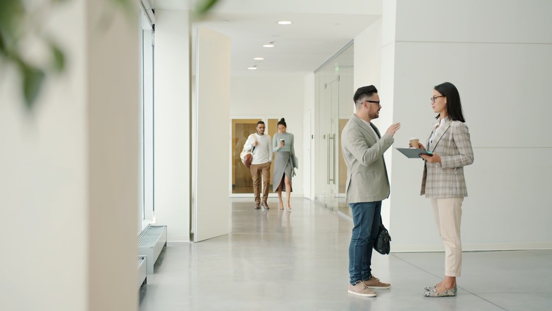 Two people talking in a modern office hallway.