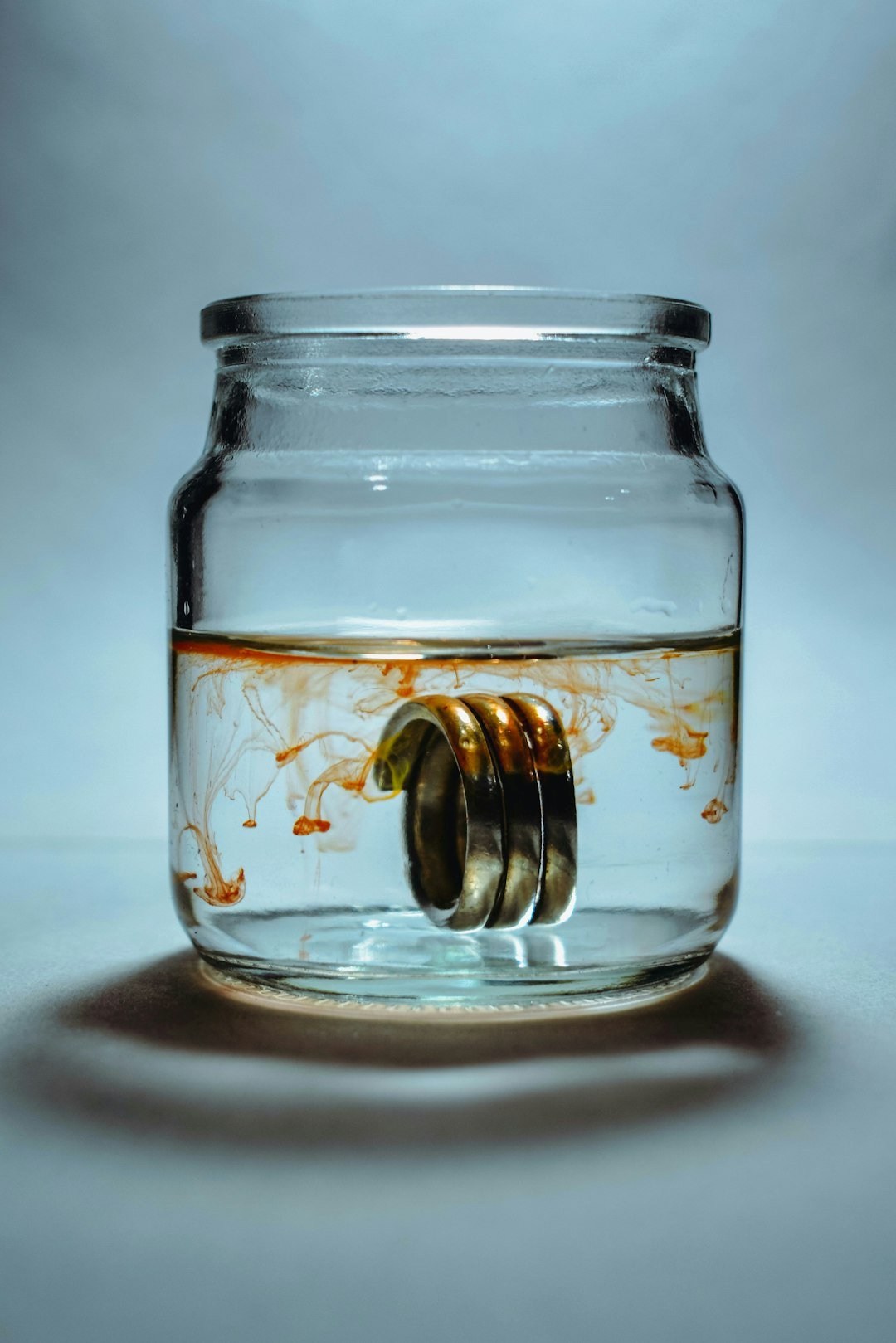 a glass jar filled with liquid and gold rings